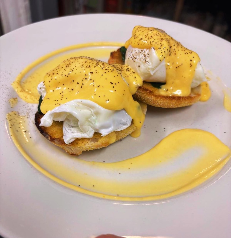 Eggs benedict with a swoosh of hollandaise across the plate